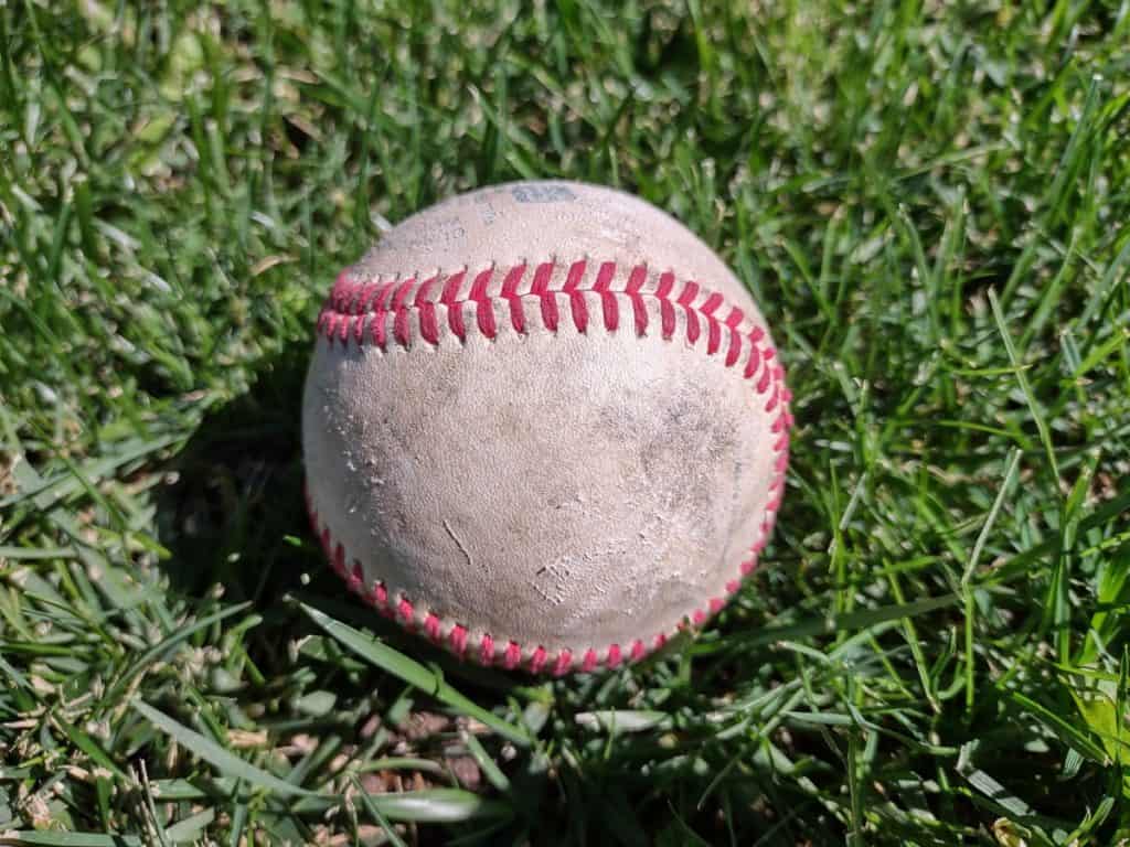Used leather baseball laying on green grass