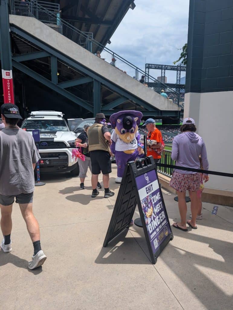 Fans meeting Dinger the Dinosaur during the 3rd inning at a Rockies game